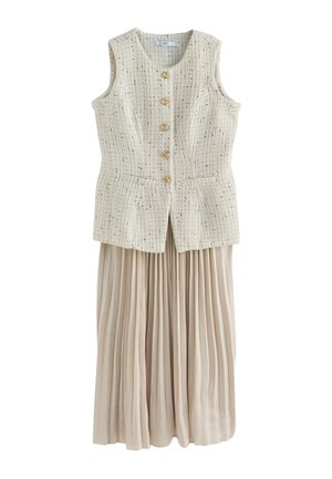 Ärmellose beige Tweedweste mit goldenen Knöpfen kombiniert mit einem langen, hellbeigen plissierten Rock.