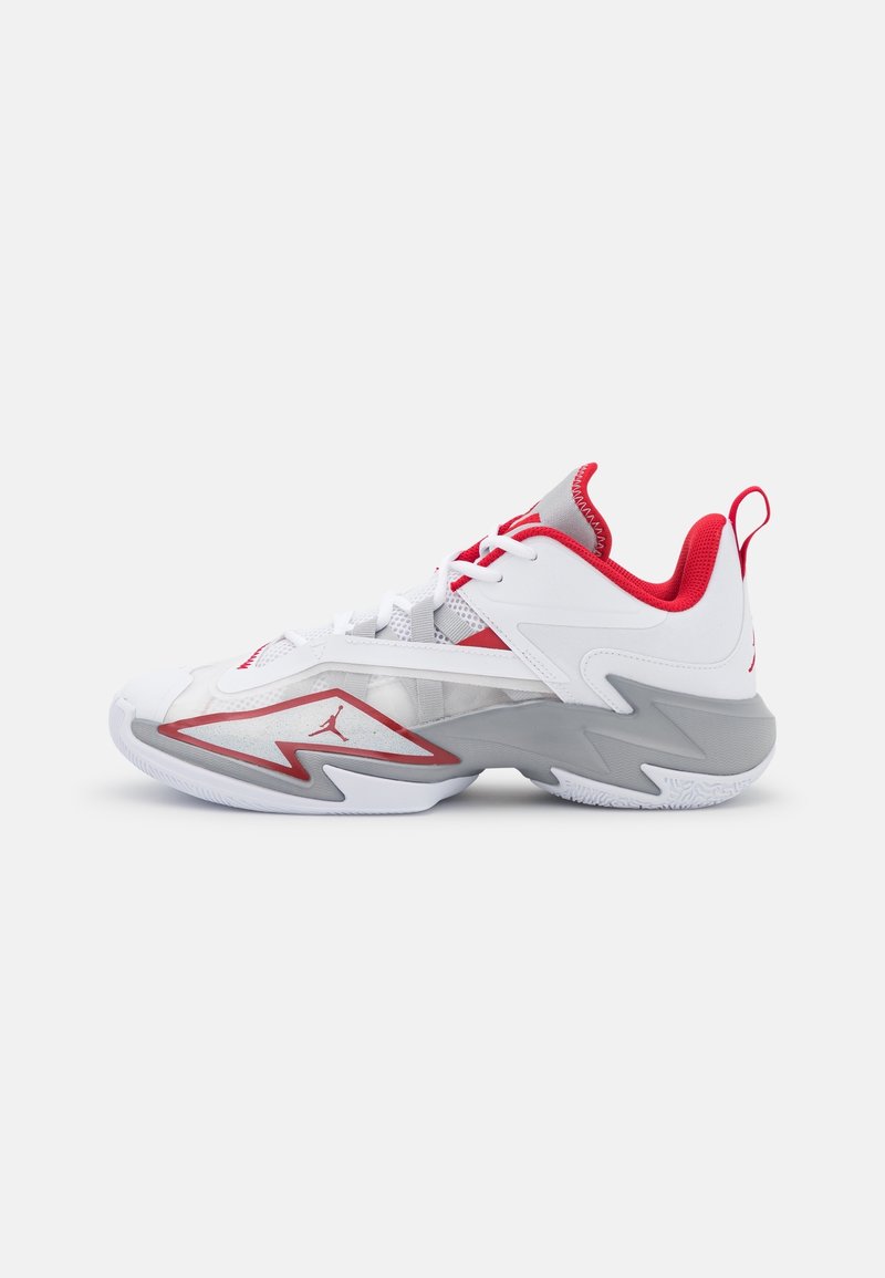 Chaussure de basket basse blanche et grise avec doublure rouge, accents rouges, lacets et semelle à motif zigzag sur fond blanc.