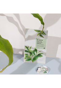 MIZON Joyful Time Green Tea Essence Mask emballage har en hvid baggrund, grafikker af grøn te blade og en mintgrøn label med tekstoplysninger.