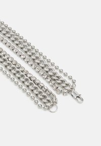 Colar de várias camadas em prata, com elos texturizados, cristais transparentes cintilantes e fecho de fecho. Acabamento suave e brilhante.