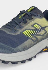 Chaussure de sport New Balance bleu foncé et jaune néon avec semelle texturée et étiquette "FuelCell" sur la languette et la semelle intermédiaire.