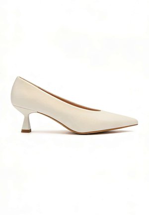 Chaussure à talon bas de couleur crème avec bout pointu et talon kitten incurvé, texture lisse, présentée sur fond blanc.