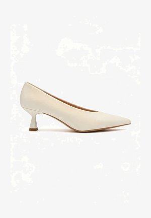 Chaussure à talon bas de couleur crème avec bout pointu et talon kitten incurvé, texture lisse, présentée sur fond blanc.