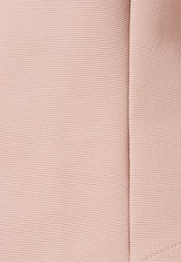 Tissu texturé de couleur rose pâle avec un motif côtelé, comprenant des coutures et des variations subtiles de teinte sur toute la surface.