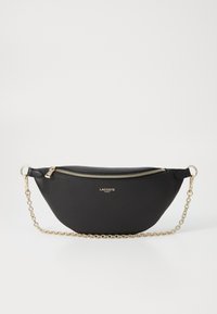 Borsa a tracolla in pelle sintetica nera con forma curvata, tracolla in catena color oro e chiusura con zip. Presenta il logo Lacoste sul fronte.