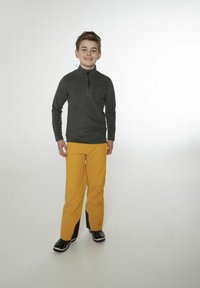 Maglione in pile a maniche lunghe di colore grigio scuro, con collo a zip; pantaloni gialli brillanti, vestibilità affusolata, dettagli neri ai polsini; stivali da neve neri e impermeabili.