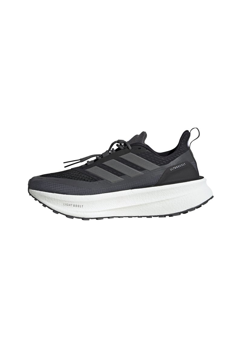 Chaussure de sport noire avec une tige en maille, trois rayures grises, une semelle épaisse blanche et des détails texturés. Présente une languette au talon.