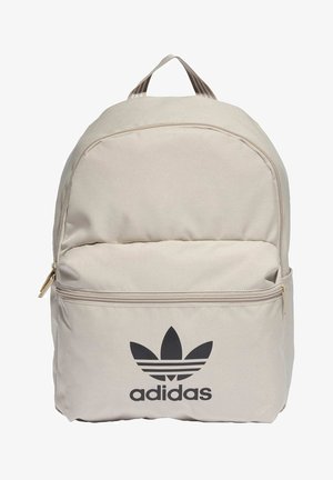 Beige Adidas-reppu, jossa etutasku vetoketjulla sekä musta trefoil-logo ja merkin nimi alareunassa etupaneelissa.