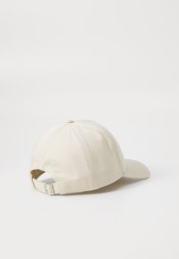 Beige katoenen honkbalpet met een gebogen klep en een verstelbare band aan de achterkant. Kenmerkt zich door gestikte details en een klassiek ontwerp.