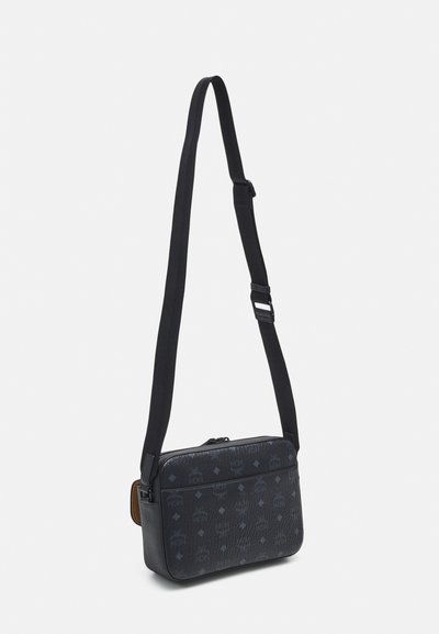 Zwarte messenger bag met een gestructureerde afwerking, voorzien van een ritssluiting, verstelbare schouderband en subtiel logo-patroon. Rechthoekige vorm, zachte stof.