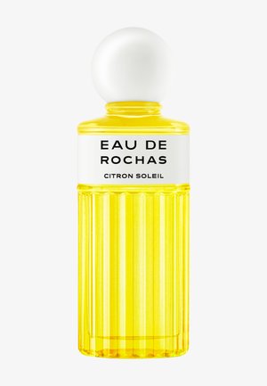 Żółta żebrowana szklana butelka perfum z białą okrągłą nakrętką i etykietą z napisem „Eau de Rochas Citron Soleil.”