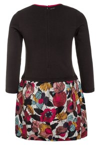 Šaty s dlouhým rukávem, černý vršek a barevná květinová sukně s červenými, modrými a žlutými listy na bílém pozadí. Zapínání na zip na zádech.