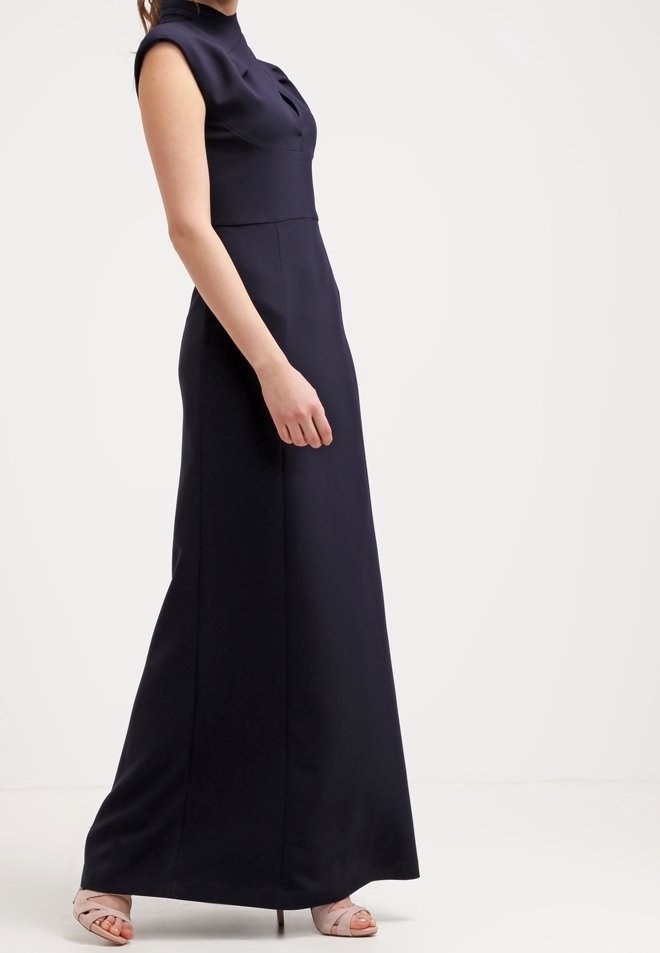 Mörkblå maxiklänning med hög halsringning, korta ärmar och en figursydd överdel. Slät, matt tyg med sid sömmar. Klacken i blockform.