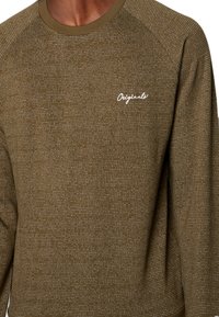 Olivengroene sweatshirt met een gestructureerd patroon, voorzien van een geribde ronde hals en witte "Originals" borduursel op de borst.