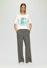 Haut court à manches courtes blanc avec un motif floral turquoise. Pantalons gris amples et baskets blanches. Design simple et décontracté.