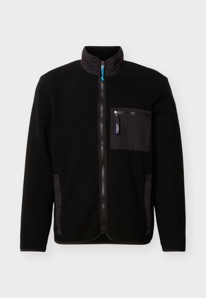 Svart fleecejakke med hel glidelås foran, høy krage, glidelåslomme på brystet og to sidelommer mot en ensfarget bakgrunn.