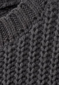 Tejido de lana gruesa de color gris oscuro que muestra un patrón texturizado detallado con puntadas diagonales y trenzadas.