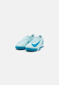 Des chaussures de sport bleu clair avec une tige texturée, arborant un logo swoosh bleu plus foncé. Conçues avec une semelle plate et des lacets pour un maintien sécurisé.