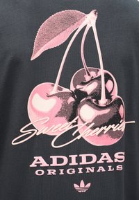 Tre ciliegie rosa con gambi e una foglia sopra il testo "Sweet Cherries" e "Adidas Originals" su tessuto scuro.