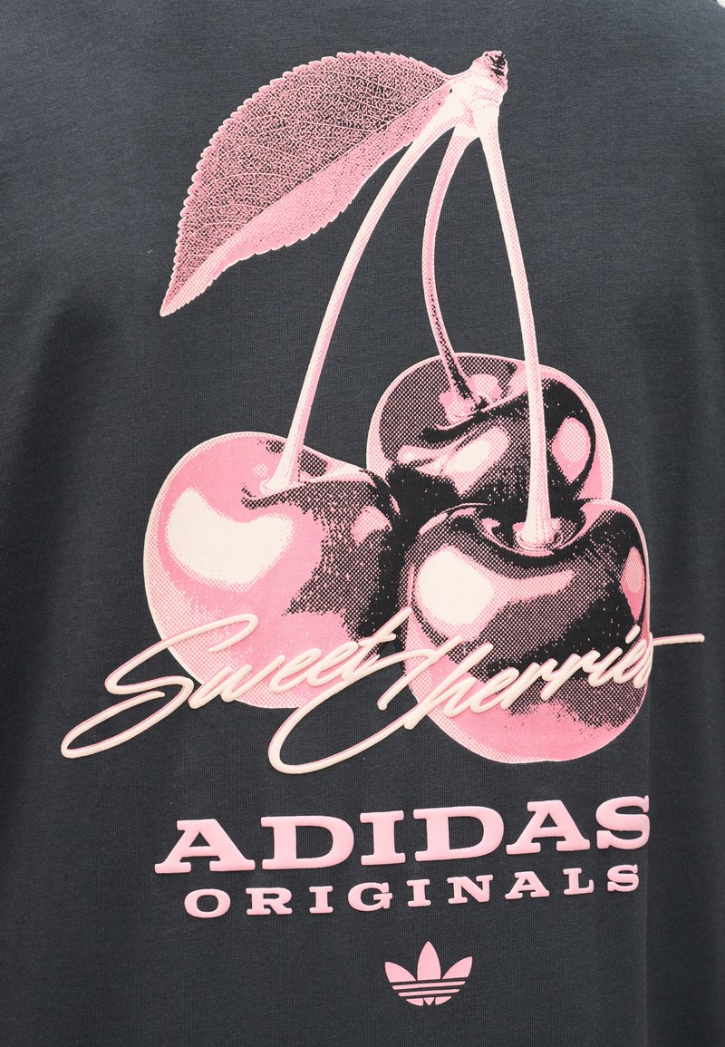 Three pink cherries with stems and a leaf above "Sweet Cherries" and "Adidas Originals" text on dark fabric.