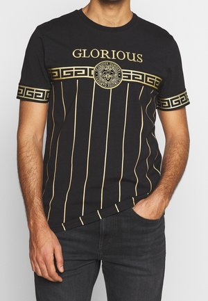 T-shirt noire avec des rayures verticales dorées, texte "GLORIOUS", logo circulaire et poignets à motif grec. Coupe décontractée avec manches courtes.