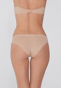 Beige Unterwäsche aus Baumwollmischung mit glatter Textur und niedrigem Schnitt. Einfache elastische Taille, minimale Nähte und keine Muster.