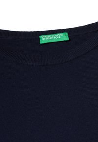Mörkblå ribbad stickad t-shirt med rund halsringning. Etikett med texten "UNITED COLORS OF BENETTON" på grön bakgrund.