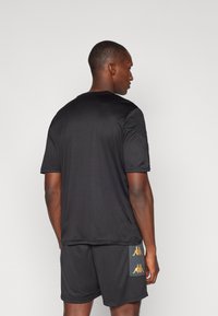 Sort atletisk t-shirt med korte ærmer, glat stof, rund halsudskæring og Kappa-logo i guld på shortsene. Enkel, funktionel design.