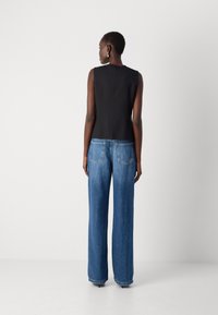 Svart ermeløs topp kombinert med høy livvidde, vide blå denimjeans med baklommer og lys vask. Slett tekstur, skreddersydd passform.