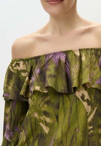 Top de hombros al descubierto con un escote volcado, en un patrón floral verde y morado, con una tela suave y texturada y un acabado elástico.