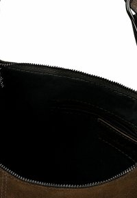 Interieur van een bruine suède tas met een zwarte voering, voorzien van een ritssluiting en een klein zakje. Soepele textuur en netjes gestikte randen.