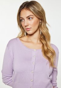 Cardigan tricotat lavandă, cu guler rotund și cinci închideri decorative cu nasturi, având o textură fină și mâneci lungi.