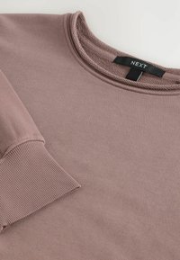 Hellblauer Sweatshirt mit gerippten Bündchen und Ausschnitt; hat eine glatte Textur; Markenetikett "NEXT" am Kragen angebracht.