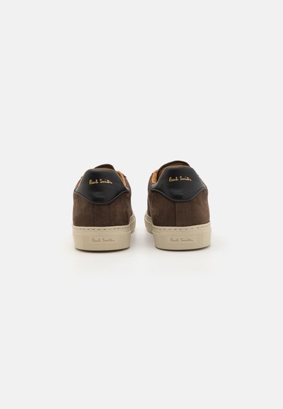Sneaker in suede marrone con accenti in pelle nera e suole in gomma beige. Presenta il logo dorato "Paul Smith" sul tallone e sulla linguetta.