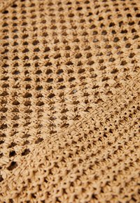 Häkelkorb aus natürlichen Fasern, in einem hellen Beige mit offenem Webmuster und strukturierter Oberfläche, die weich und flexibel ist.