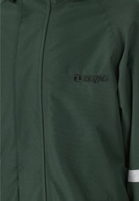 Groene jas van structuurstof met een ritssluiting en reflecterende streep. Voorzien van een zwart geborduurd logo op de borst.