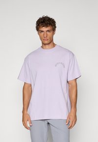 Lavendel bomull oversized t-skjorte med korte ermer og rund hals. Har teksten "STUDENTER" i buet skrifttype på venstre bryst.