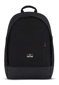 Mochila negra con textura suave, forma redondeada y parche con logo. Cuenta con un bolsillo frontal con cremallera y correas de hombro ajustables.