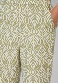 Spodnie w liście w kolorze oliwkowym i białym, wykonane z miękkiego materiału. Posiadają boczne kieszenie i elastyczny pas.
