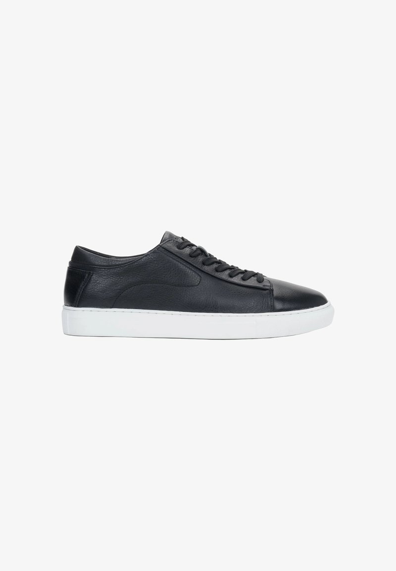 Czarny niski skórzany sneaker z czarnymi sznurówkami i grubą białą gumową podeszwą, pokazany z boku na białym tle.