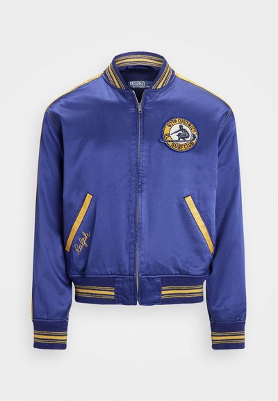 Blue satin bomber jacket with yellow striped accents, front zip closure, embroidered surf club logo, and side pockets.