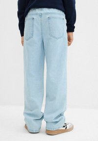 Jeans in denim blu chiaro a gamba dritta con una vestibilità comoda, dotati di tasche posteriori e una vita parzialmente elasticizzata, abbinati a sneaker.
