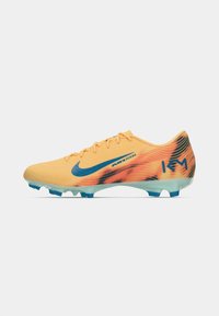 Nike jalgpallijalatsid kollases toonis siniste aktsentidega. Tekstuuriga ülemine osa, millel on musta värvi üleminekuga gradientmuster. Kerge tallaga, millel on läbipaistvad sinised nupud.