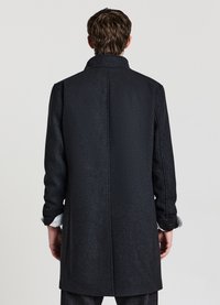 Cappotto nero dal taglio dritto, maniche lunghe e collo rialzato. Tessuto liscio con una leggera lucentezza, senza motivi o dettagli visibili.