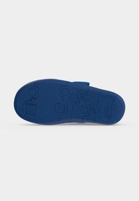 Semelle de chaussure bleue avec des motifs de bande de roulement circulaires et rectangulaires, vue par dessous sur fond blanc.