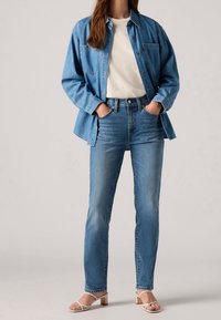 Denimskjorta i ljusblått, kragn design med två bröstfickor, parat med hög midja blå jeans och vita sandaler med remmar och klack.