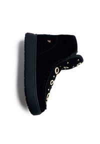 Bota negra de ante hasta el tobillo con ojales dorados circulares a lo largo del lado, costura en contraste y una suela de goma negra gruesa.