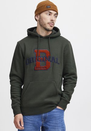 Hoodie vert avec une poche kangourou, présentant un grand logo brodé "D" rouge et bleu ainsi que le texte "ORIGINAL". Bords côtelés aux poignets.