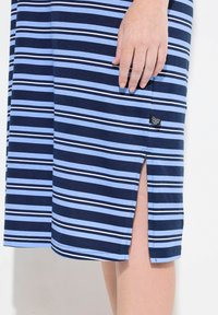 Abito a righe blu e bianche con uno spacco laterale, realizzato in un tessuto morbido. Include un piccolo etichetta del marchio vicino all'orlo sul lato sinistro.