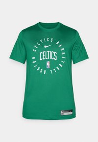 Camiseta verde de Nike con el texto "Boston Celtics Basketball" en blanco, diseño redondo, con el logo de la NBA y una etiqueta en la esquina inferior derecha.